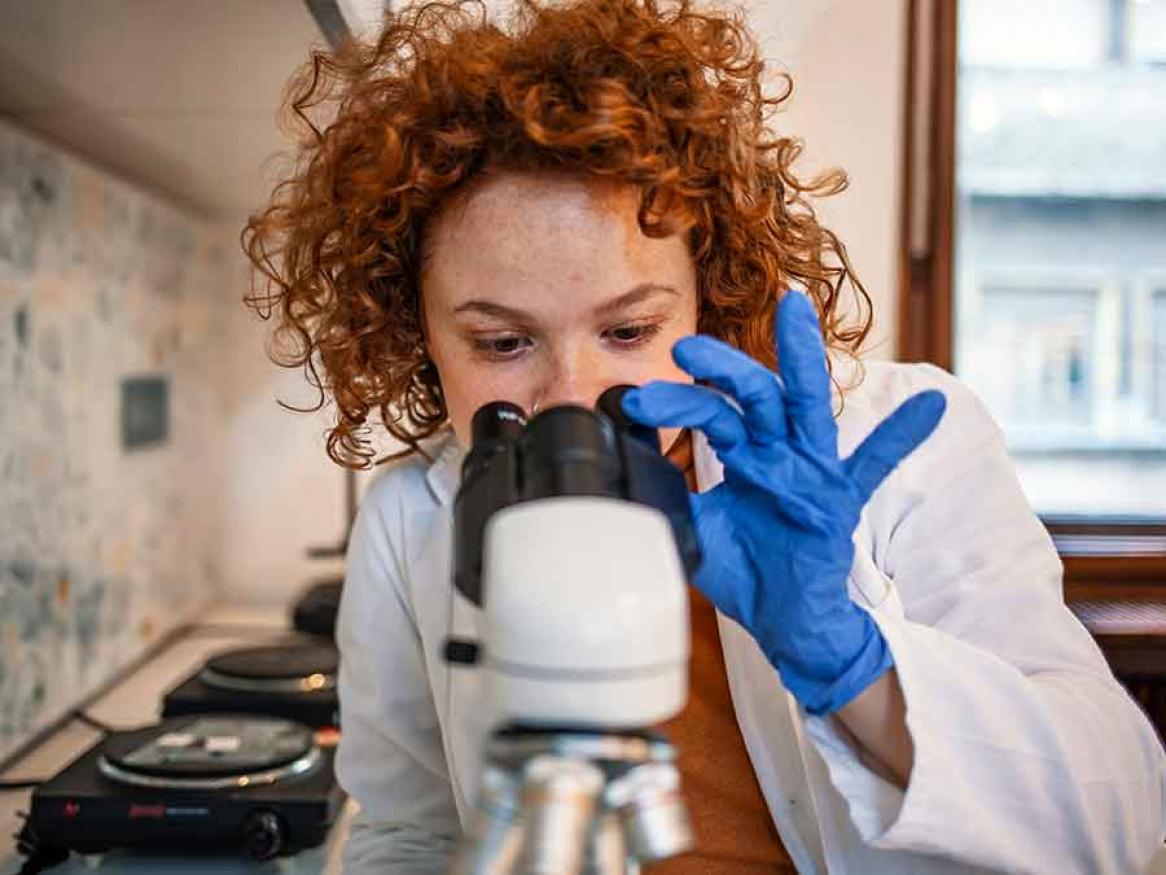A female scientist looking through a microscope