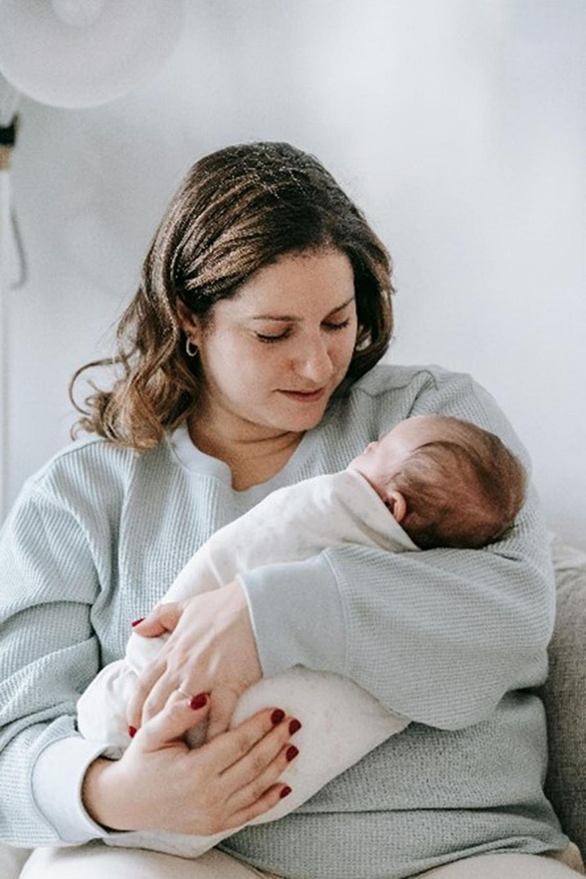 A young mum cradling a newborn baby