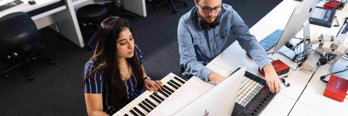 Students sit at piano keyboard