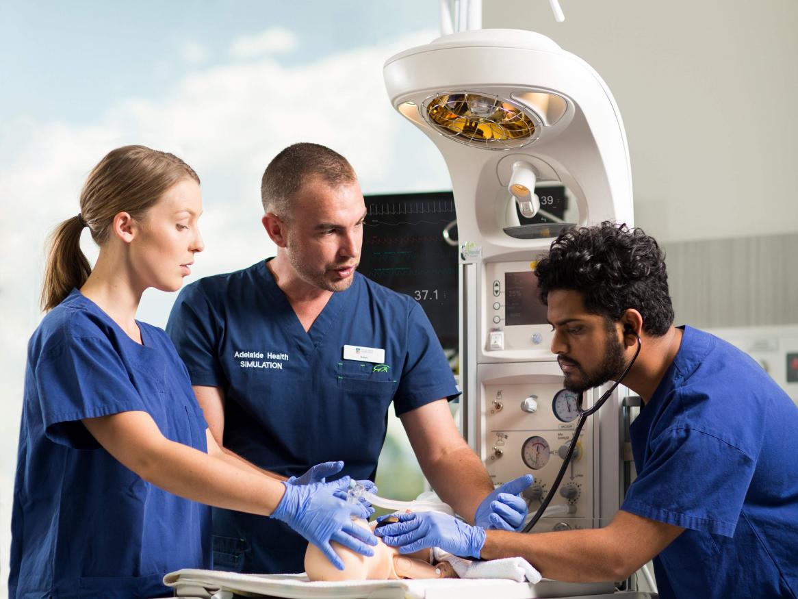 Two medical students and instructor in medical simulation performing tests on a baby