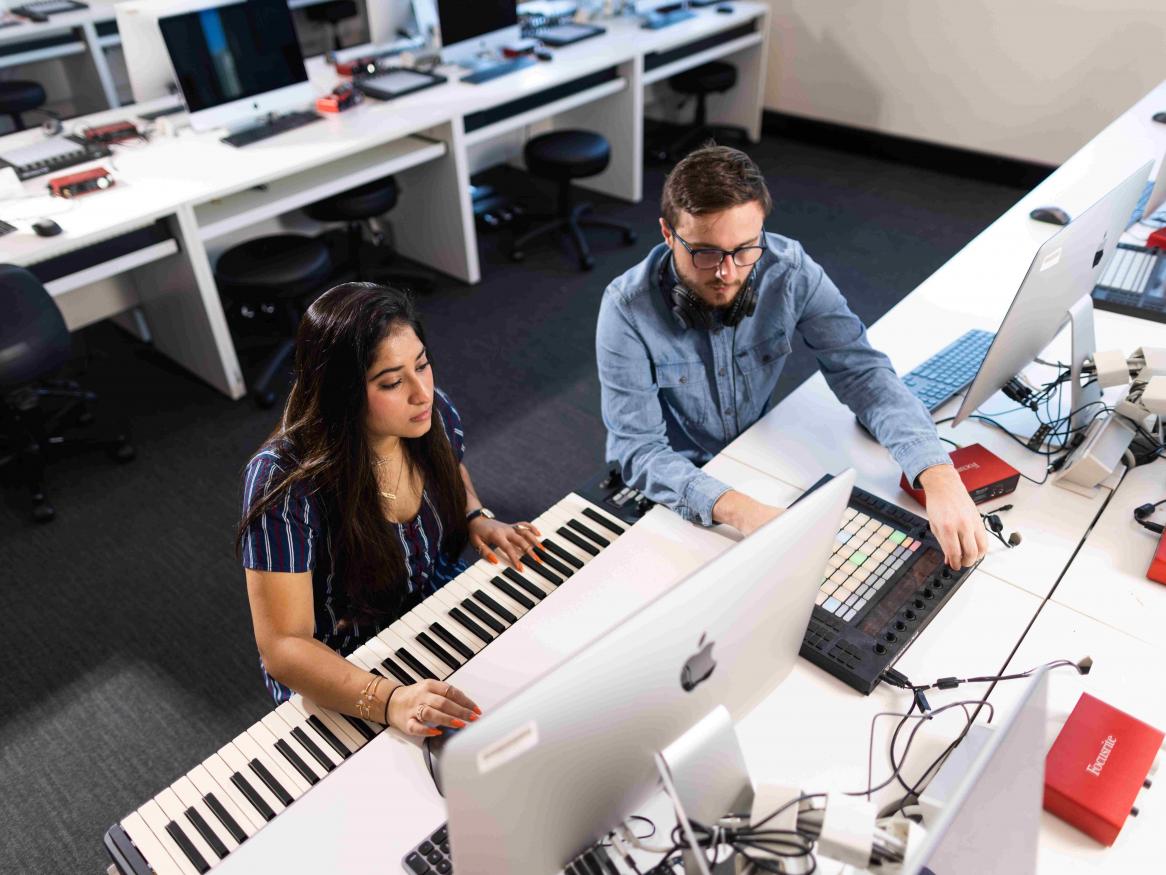 Students sit at piano keyboard