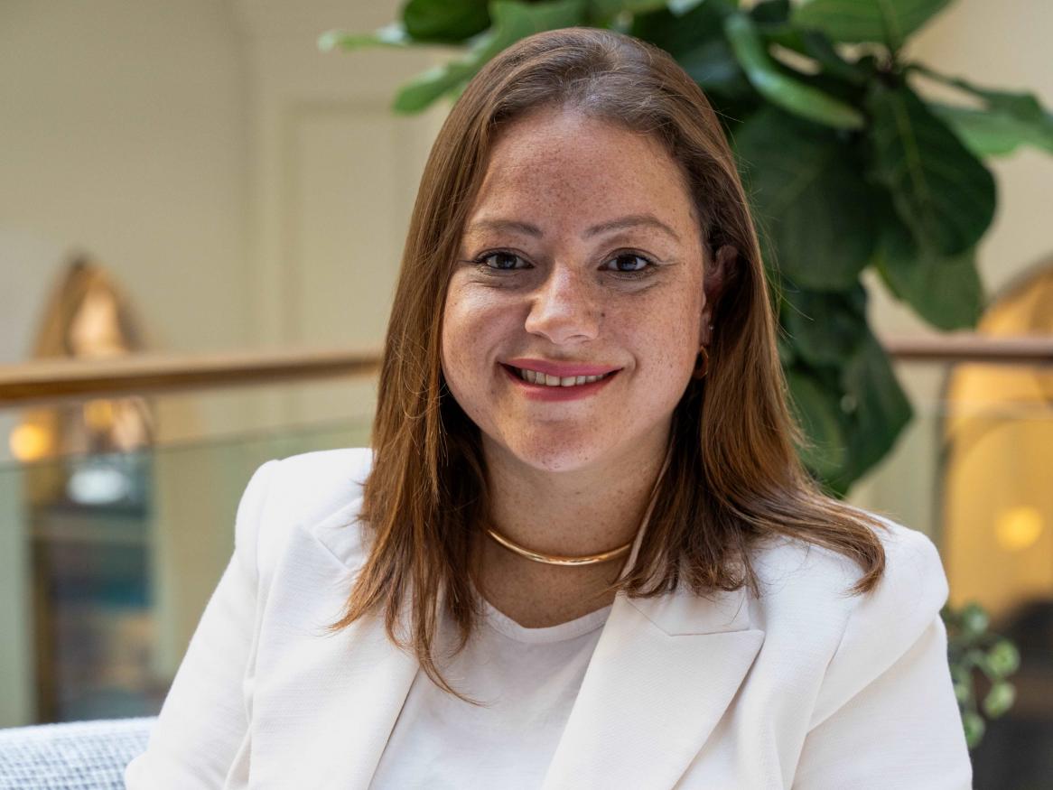 Photo of Debora Compri smiling wearing a white jacket and top