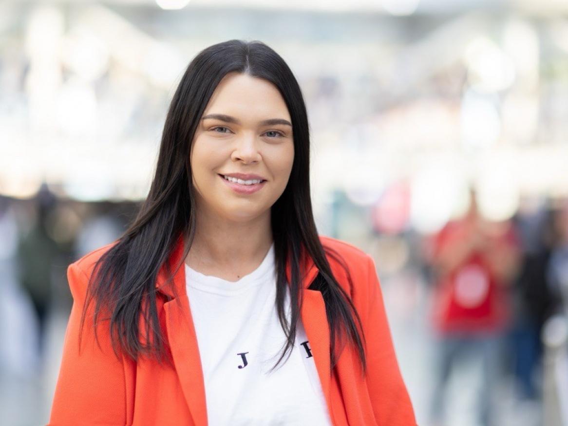 Photo of Kira Mackay wearing a red jacket and white top