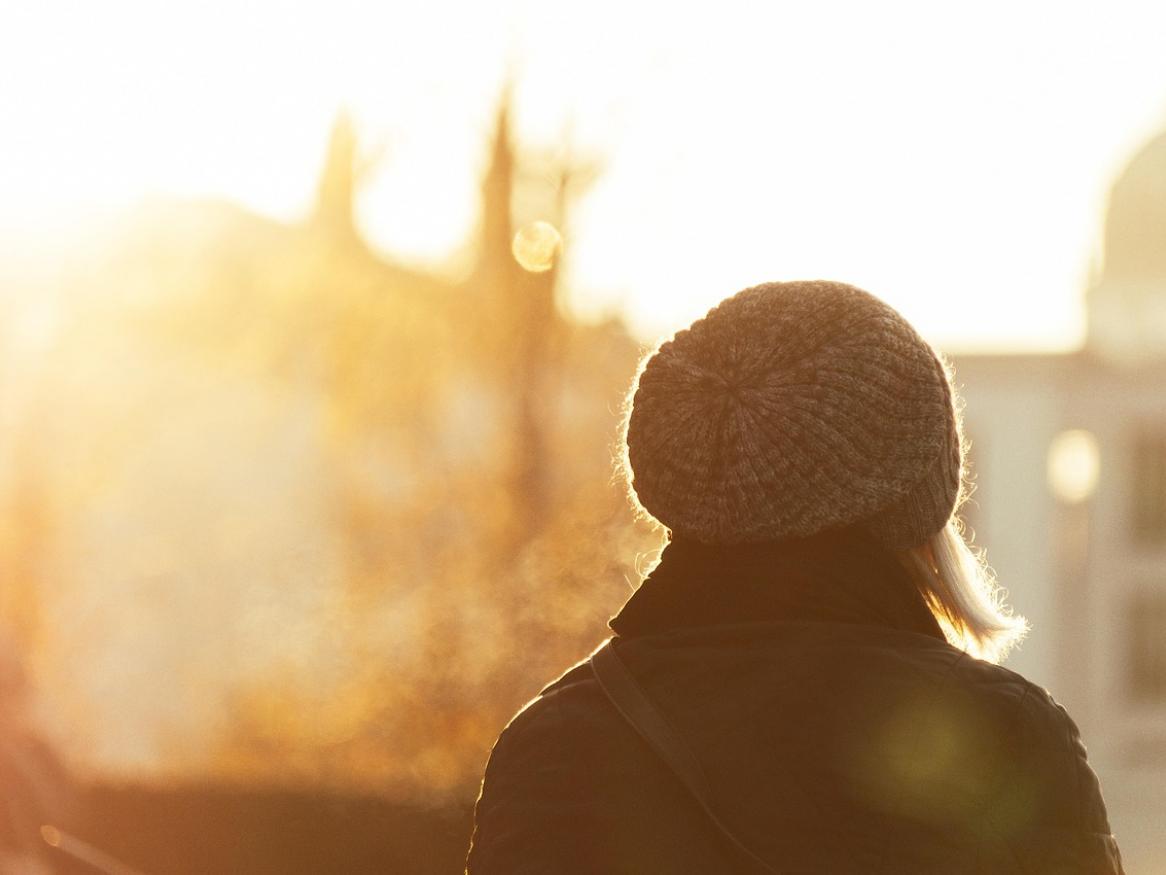 Person with knitted cap facing toward bright sun