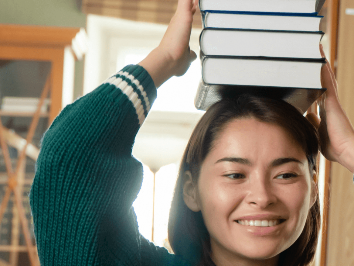 student balancing books on head