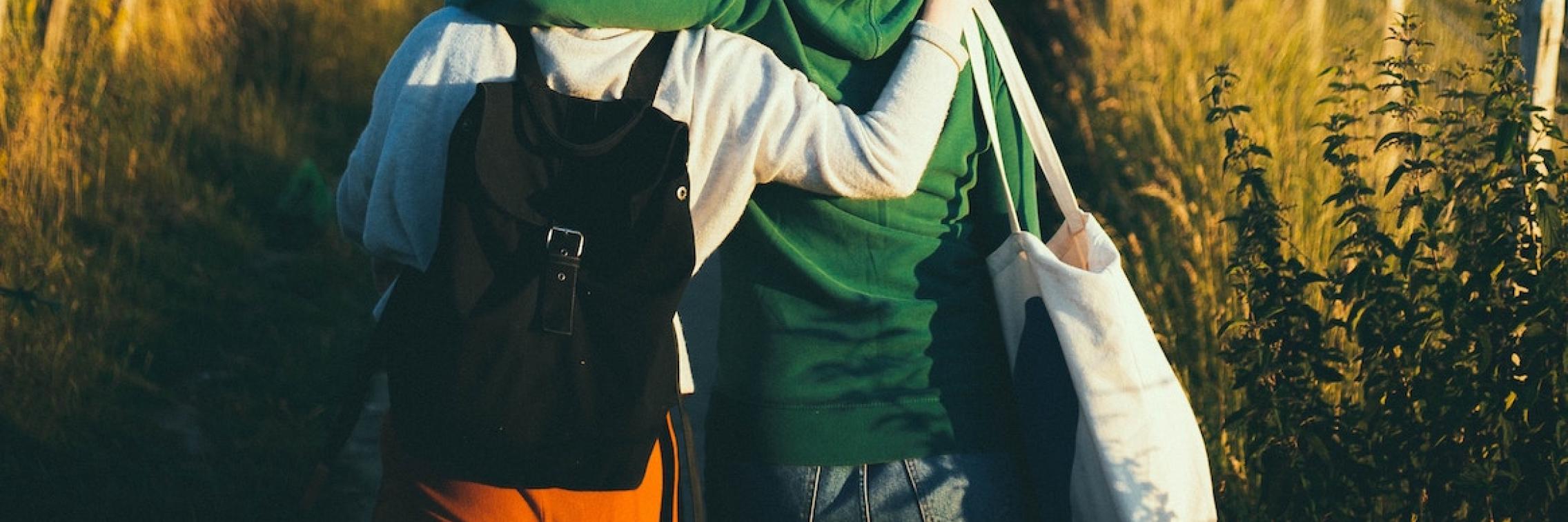 Two friends walking together on a path in a field.