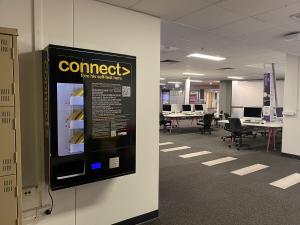 Photo of CONNECT machine attached to wall with purple zone computers in the background, Hub Central Level 3