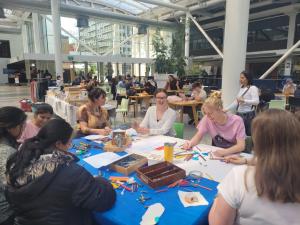 People sitting in Hub Central colouring during a Mental Health Awareness month event supported by volunteers