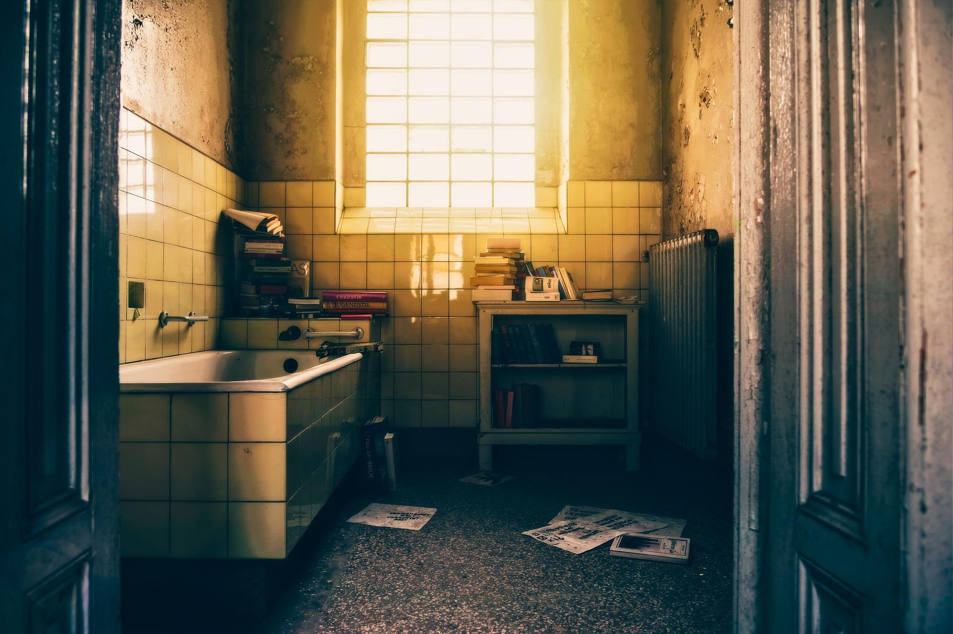a dirty bathroom with books and magazines strewn everywhere