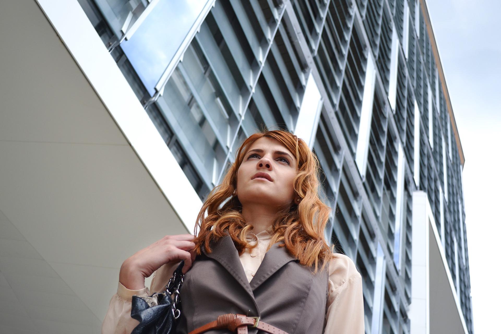 a young woman in corporate wear walks past a skyscraper