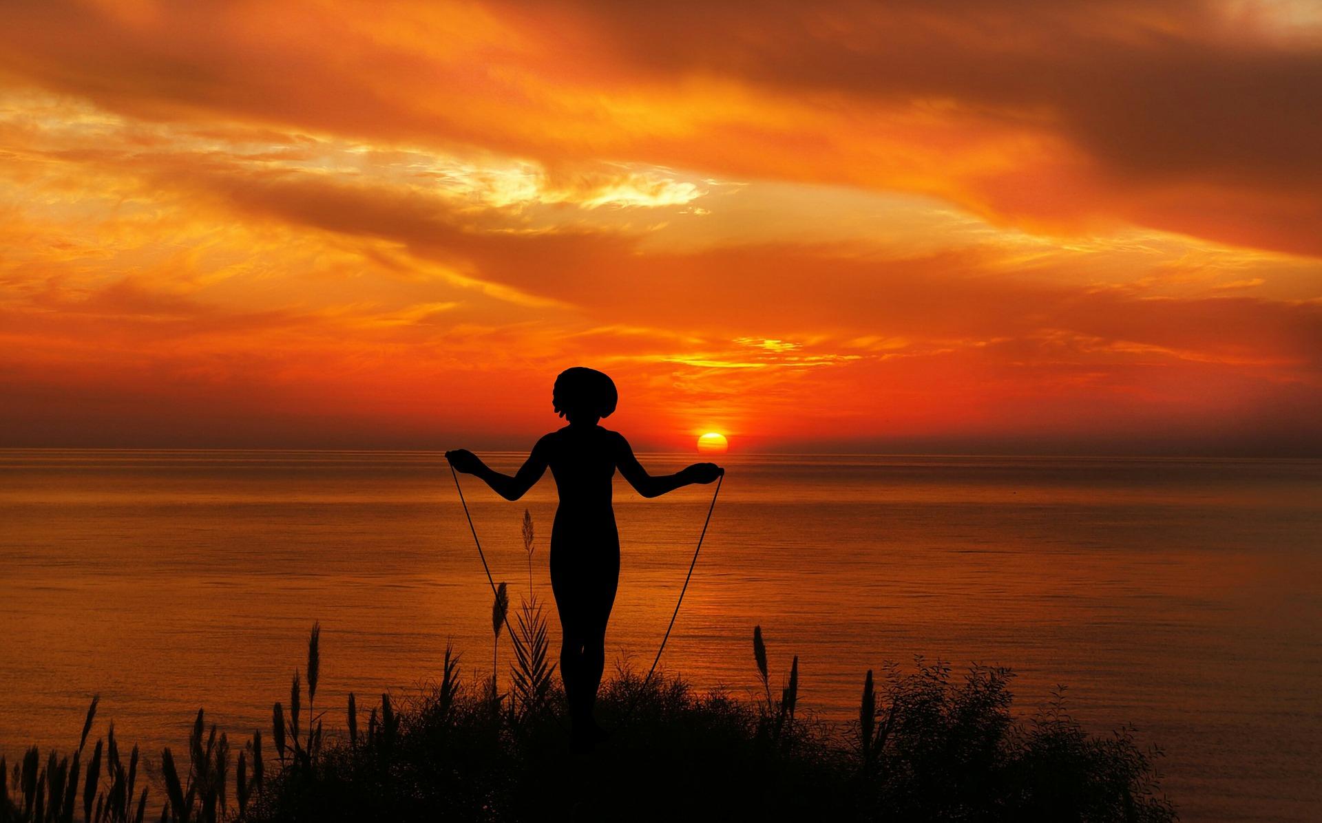 girl skipping rope behind sunrise