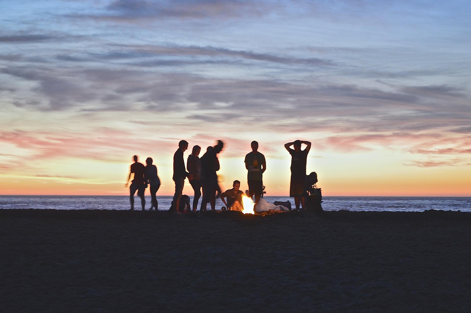 A group stand around a campfire