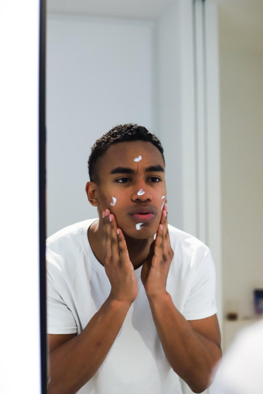 Man putting on face cream in front of mirror