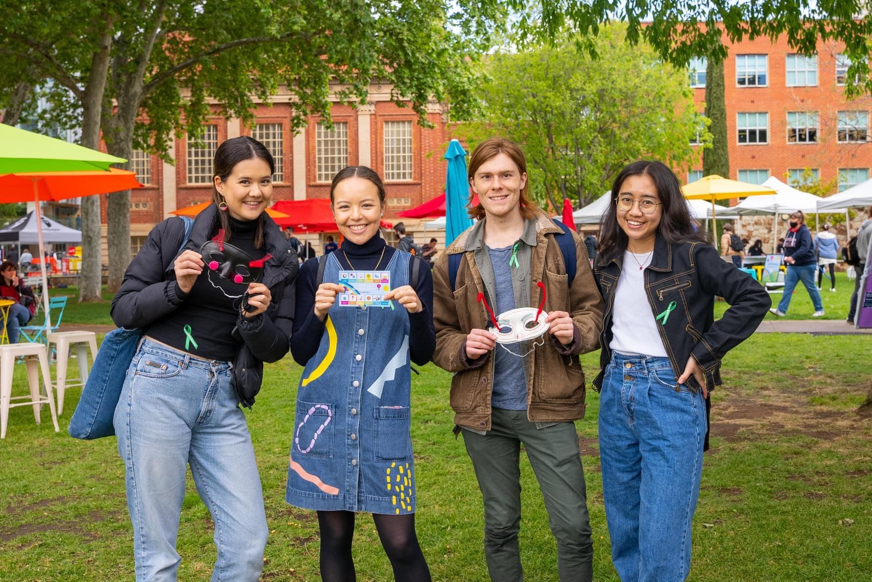 four students standing on lawns smiling at camera