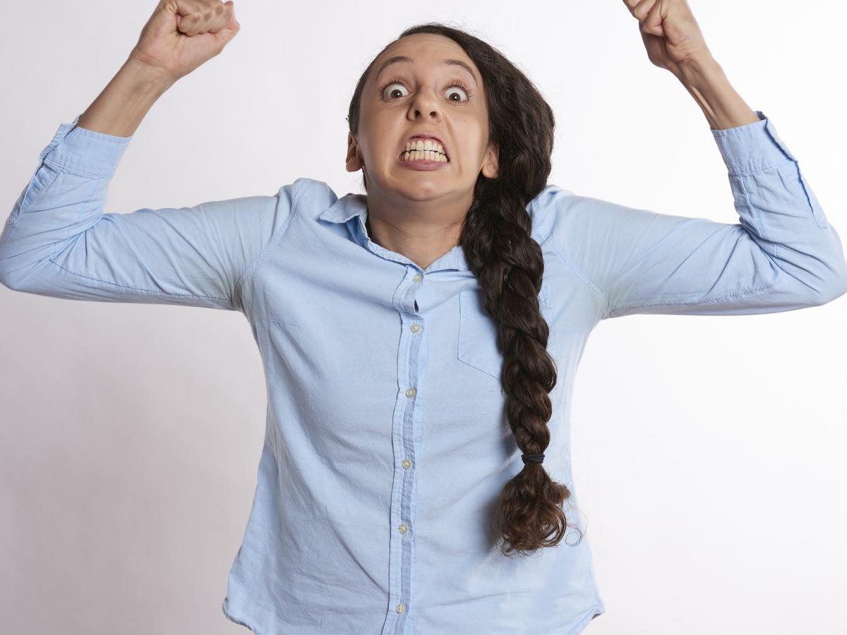 Angry woman raises arms in frustration.