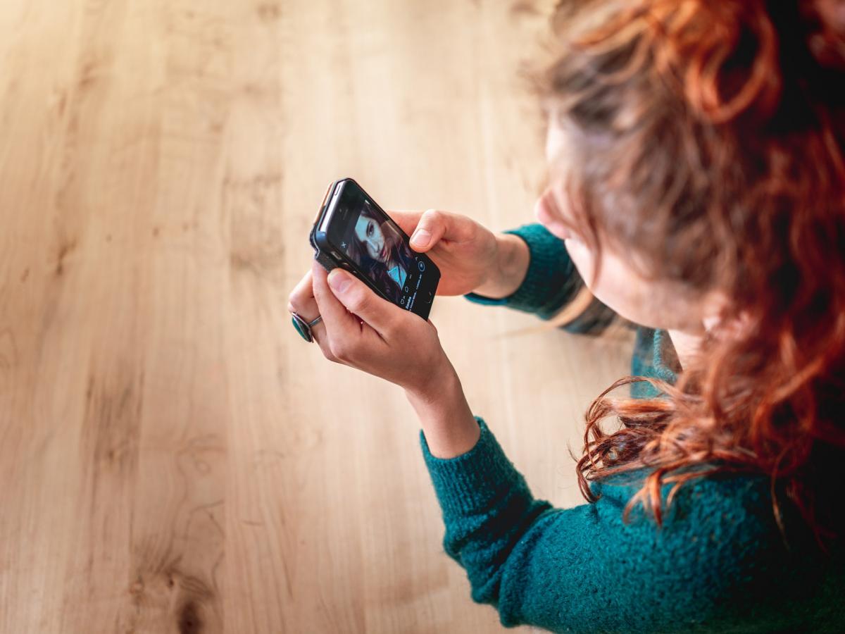 Looking down on red haired person viewing mobile screen in video call
