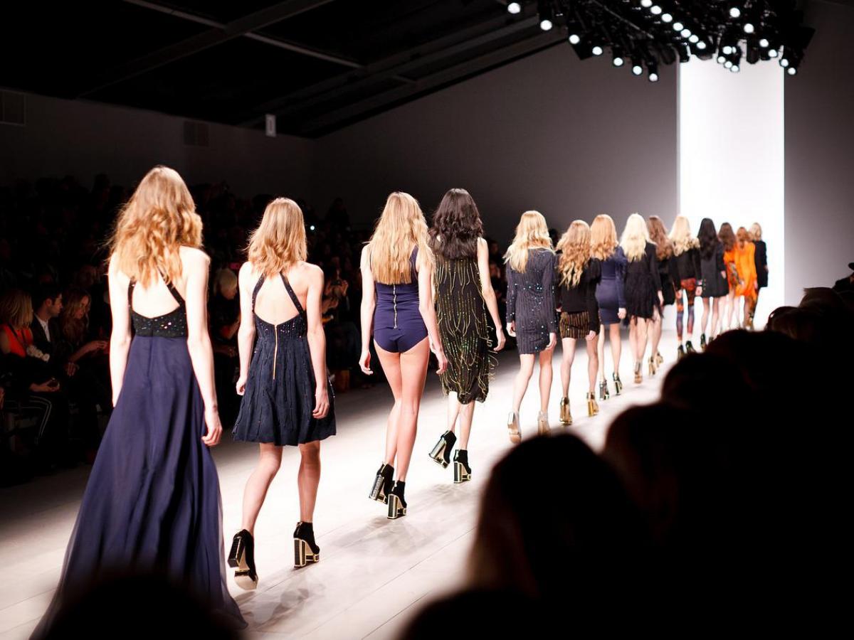 Models wearing dark colours walking down a catwalk
