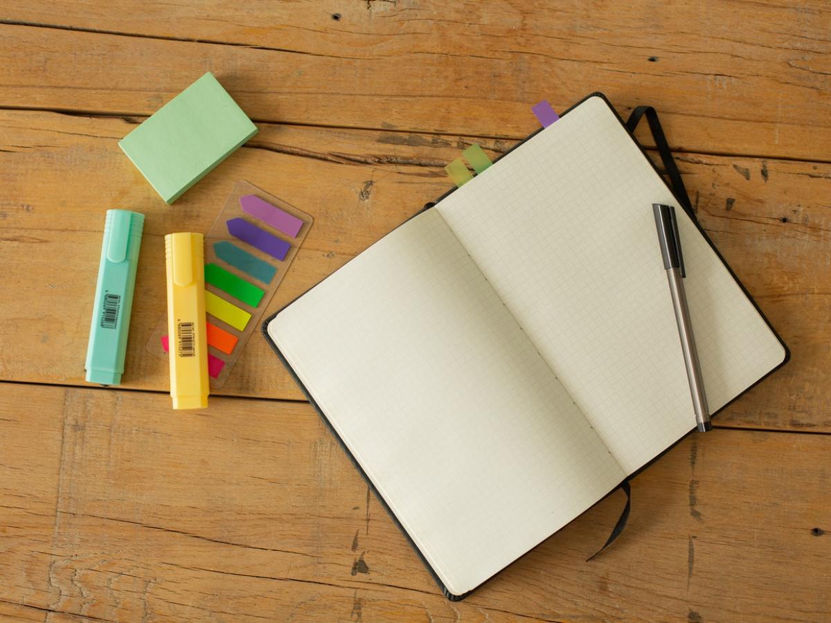 Coloured highlights and sticky notes next to an open notebook on a table