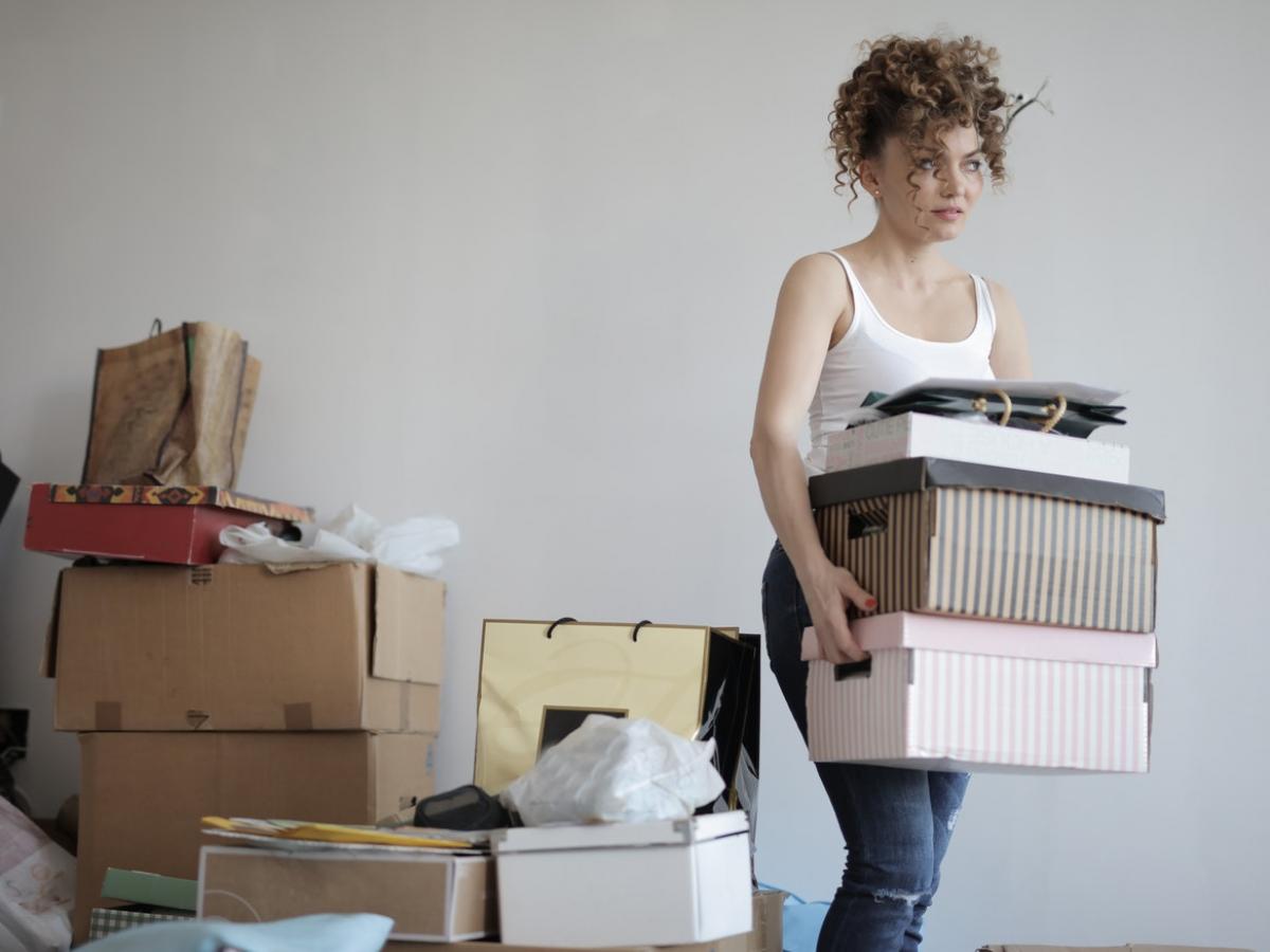 Young woman in a white tank top carrying packing boxes