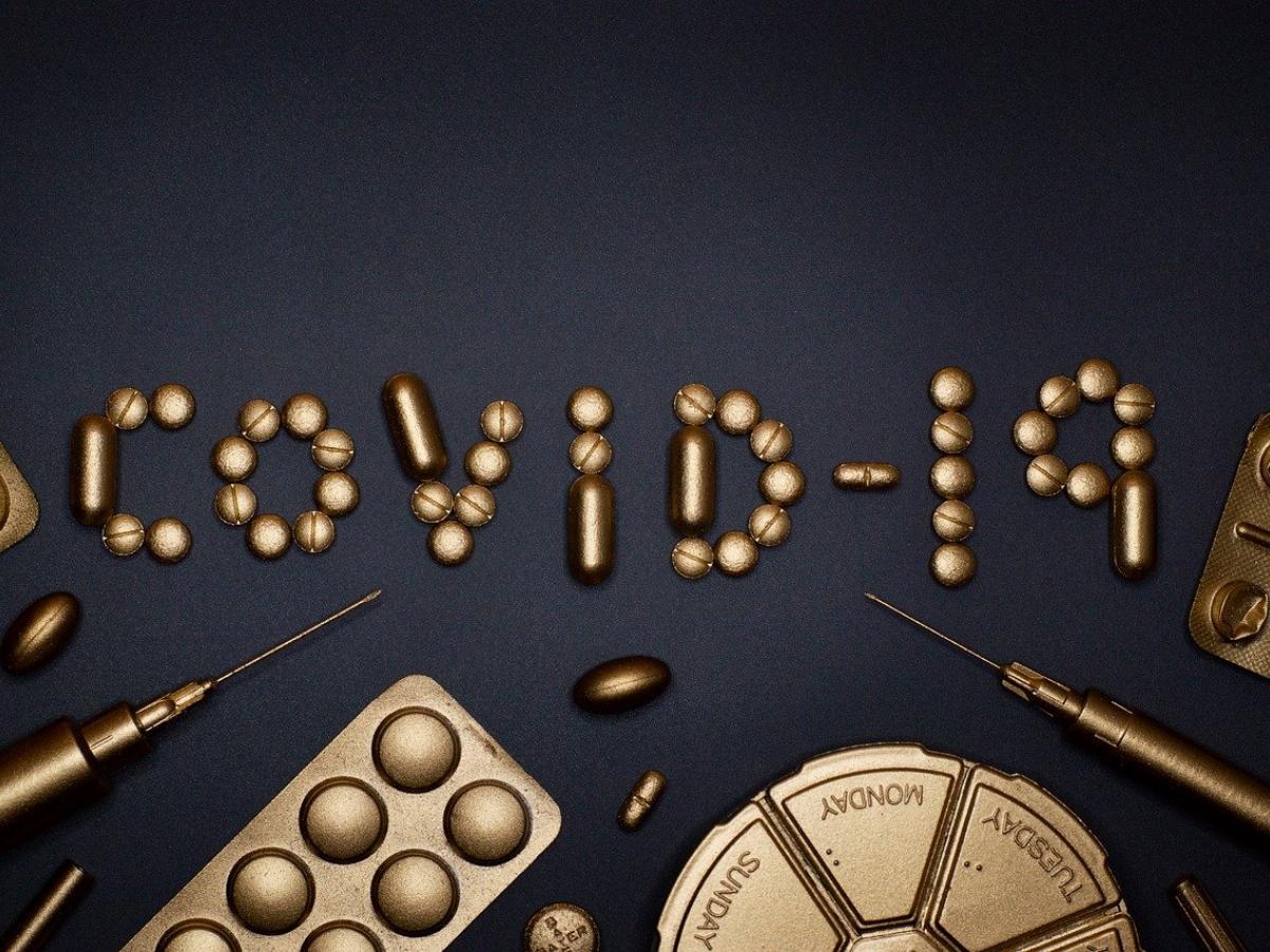 A group of pills on a table in the formation of the word 'COVID-19'.