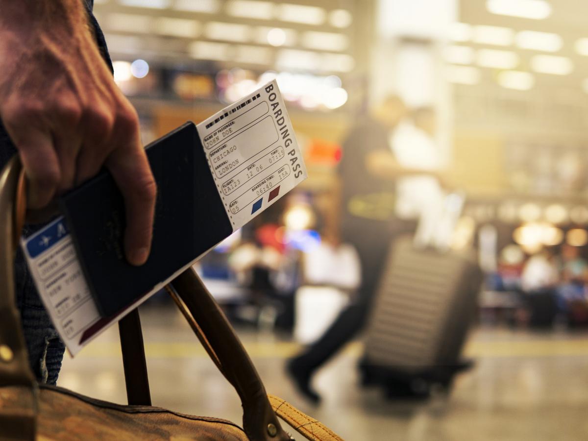 close-up of a person's hand at the airport holding their passport and boarding pass.