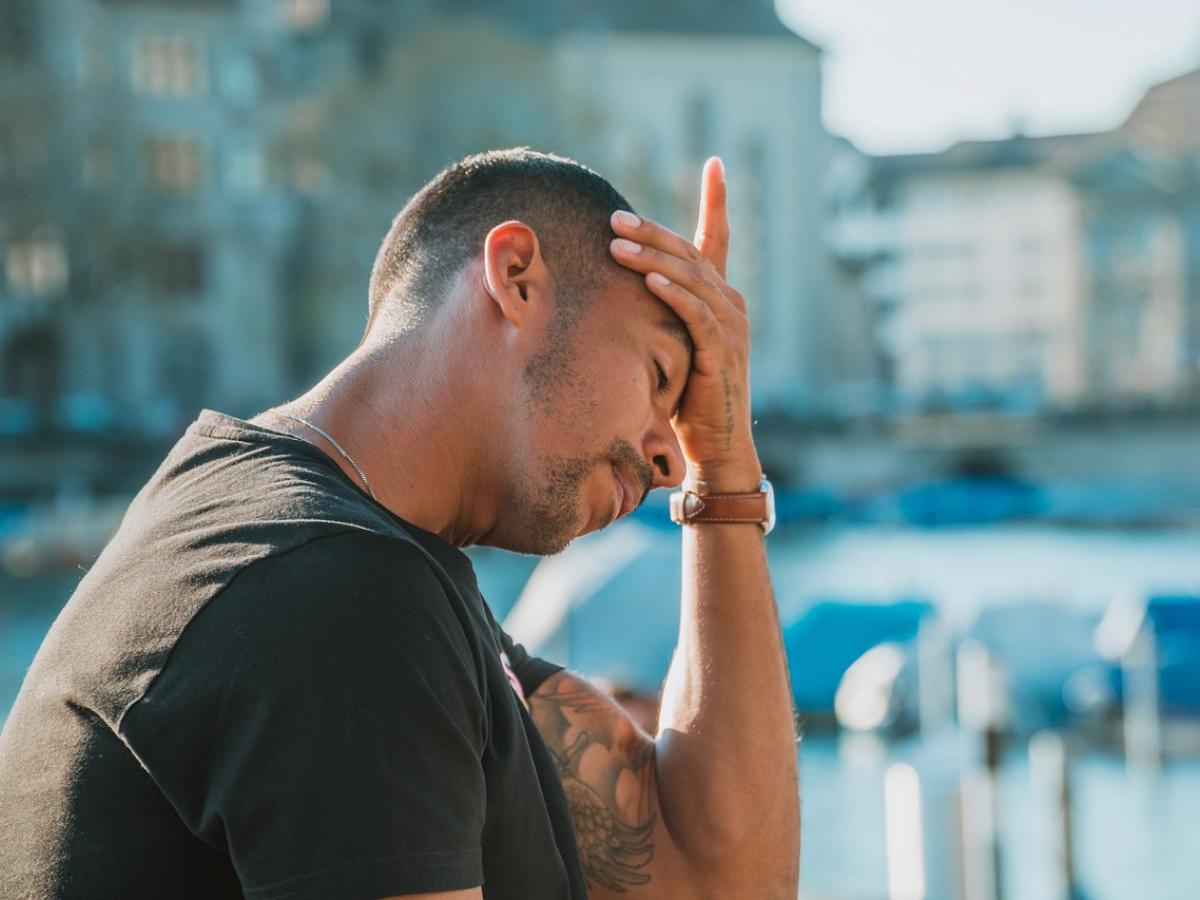 A man holds his head, looking stressed.