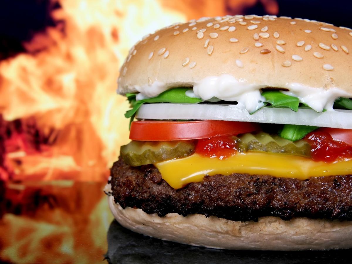 A junk food burger, with flames behind it.