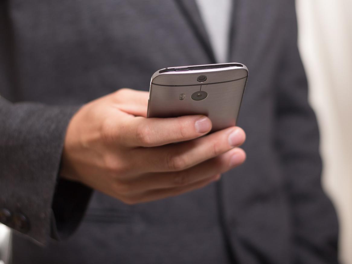 Man holding smartphone out in front of himself.