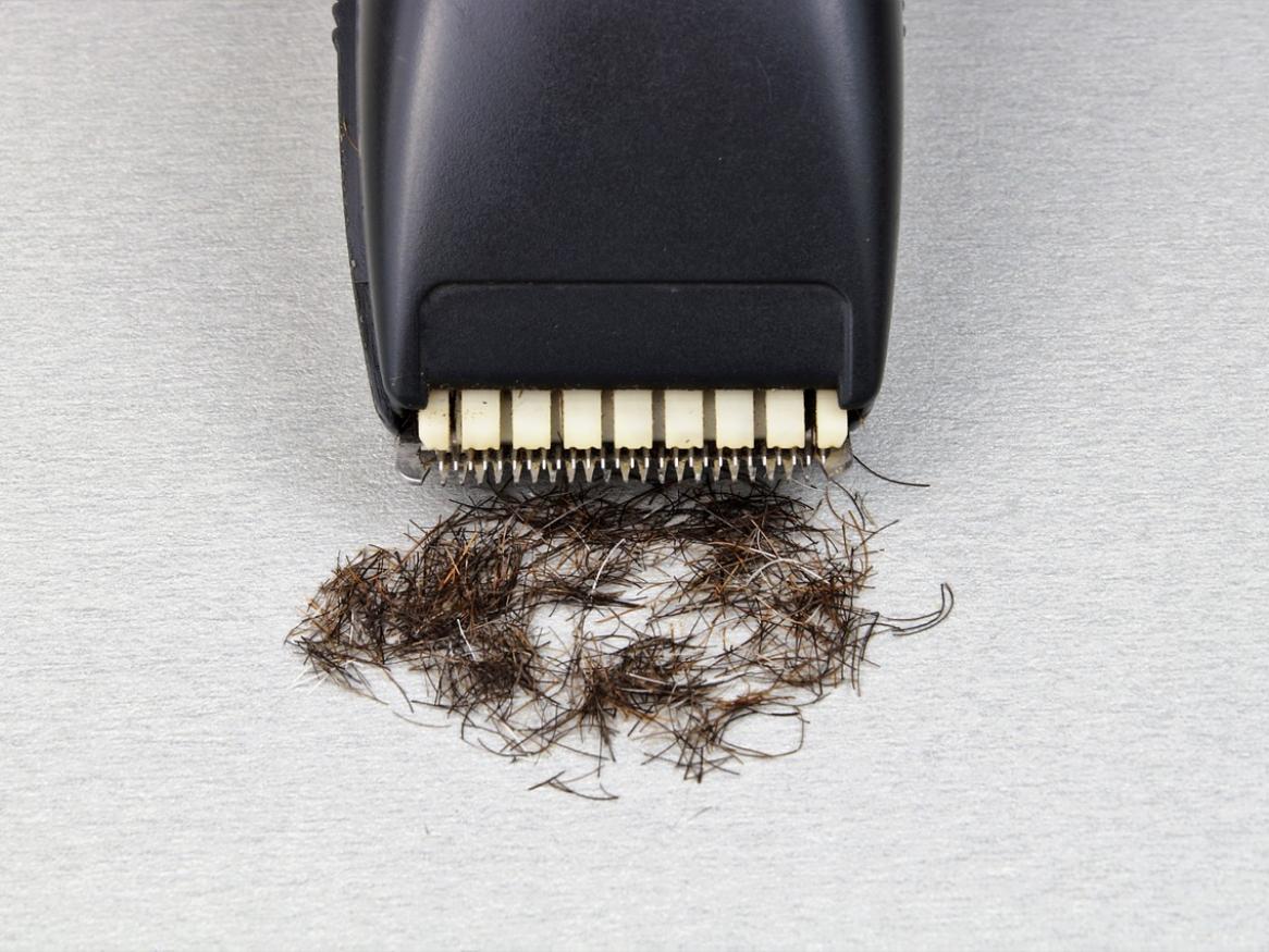 an electronic razor with bits of shaved hair at the end