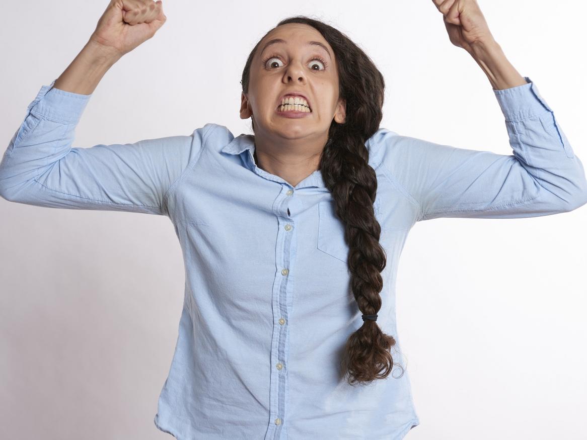 Angry woman raises arms in frustration.