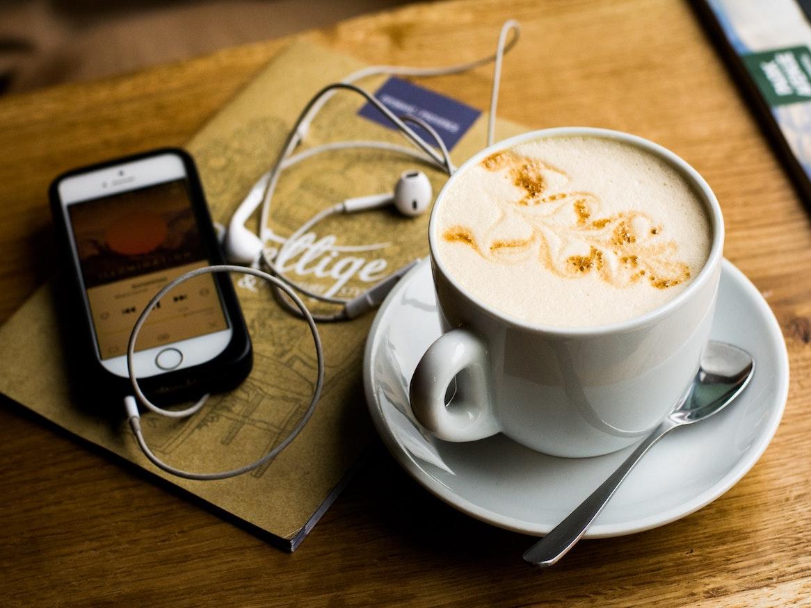 Coffee and a phone with earphone on a table