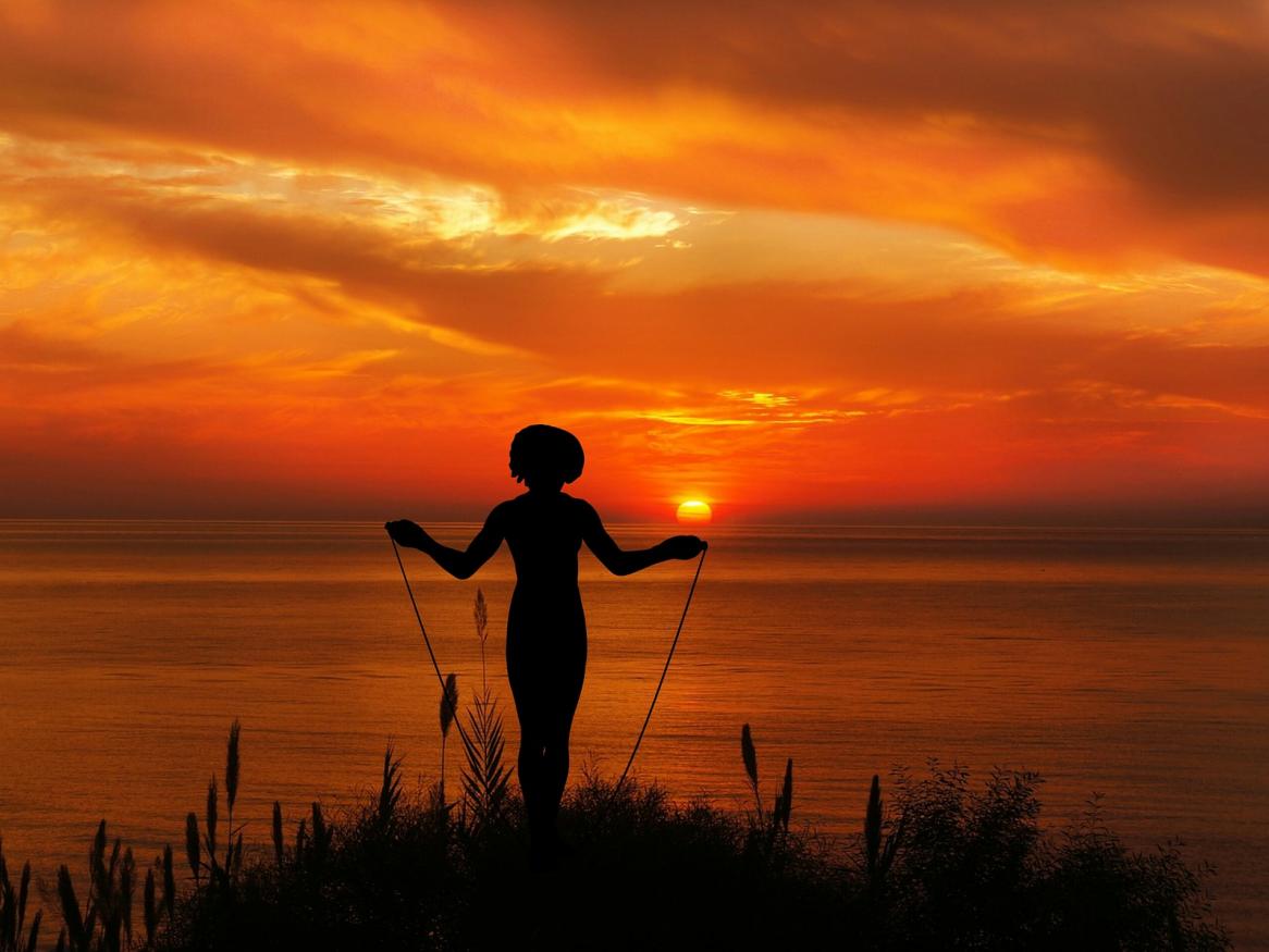 girl skipping rope behind sunrise