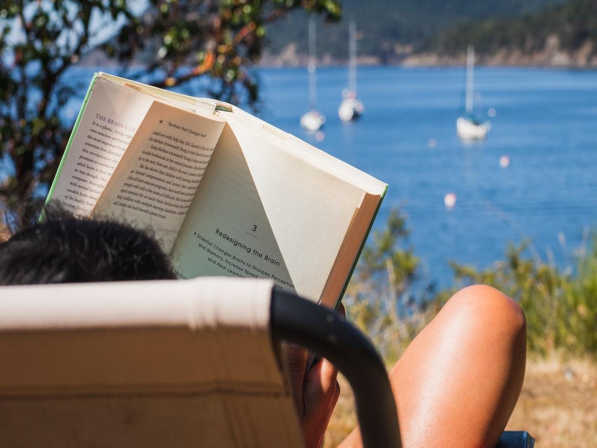 person reading a book by the ocean