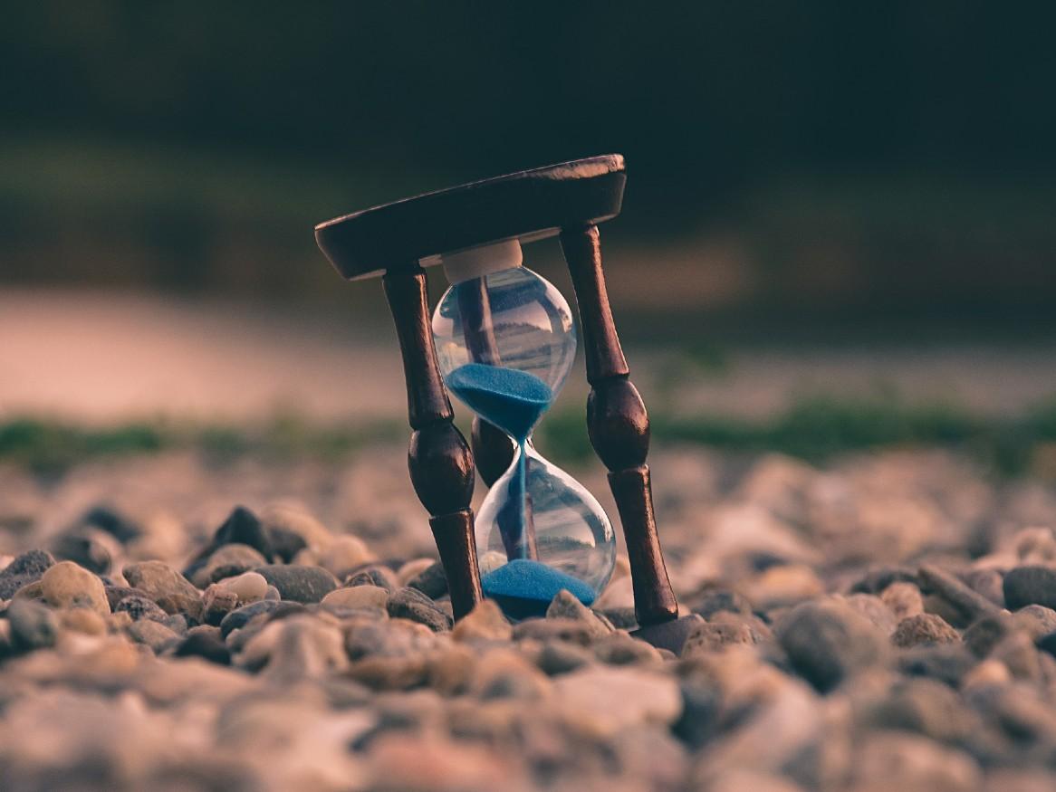 Selective focus photo of brown and blue hourglass on stones by Aron Visuals on Unsplash.com