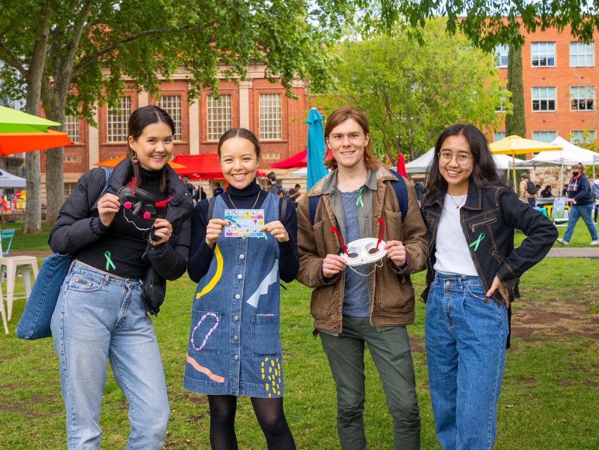 four students standing on lawns smiling at camera