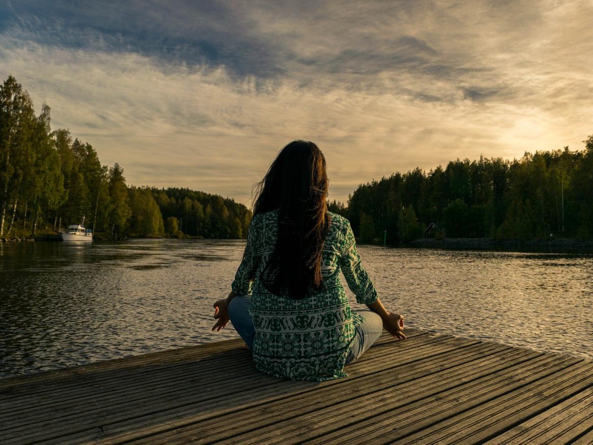 girl meditating in front of lake