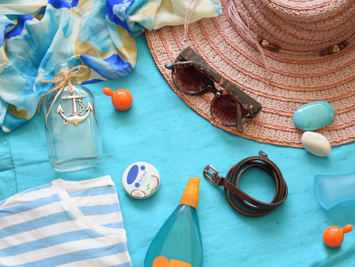 towels, hats, sunglasses on a blue mat at the beach