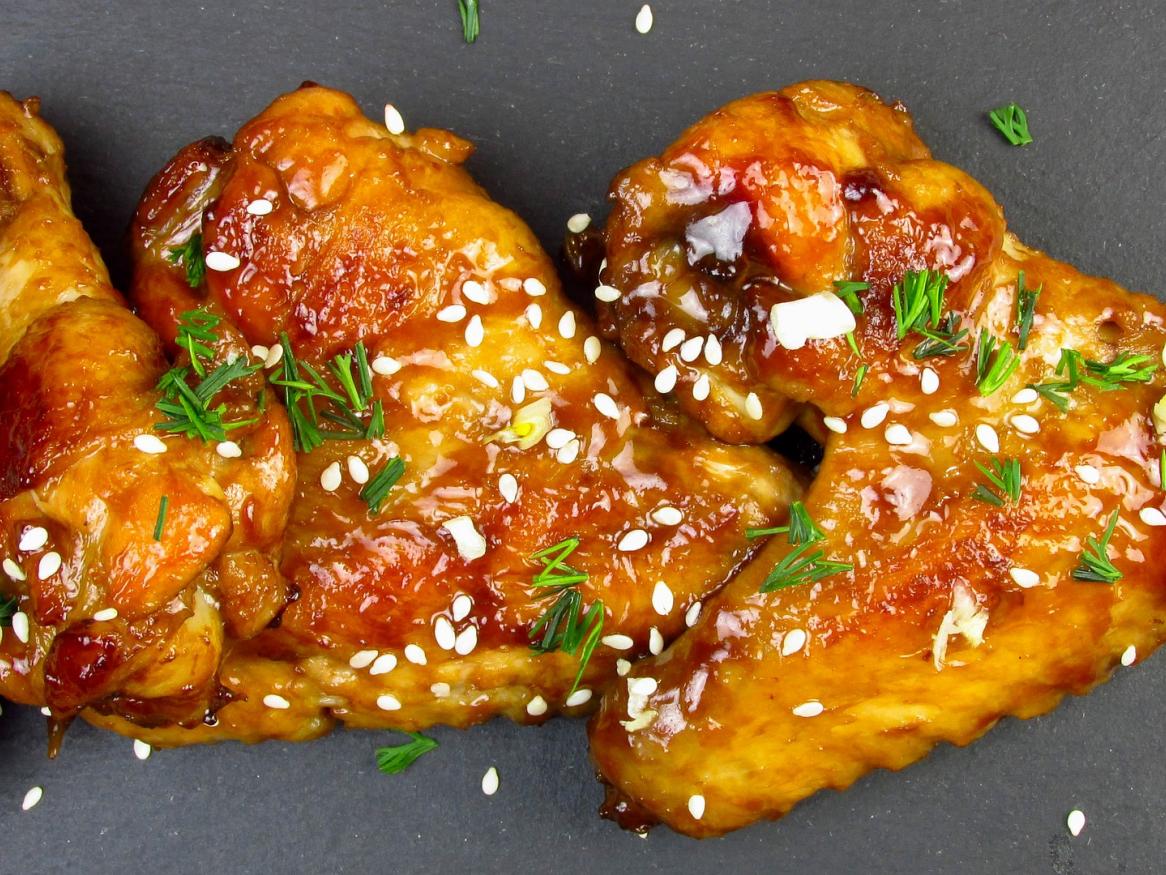 Cooked chicken wings on a grey plat with herbs