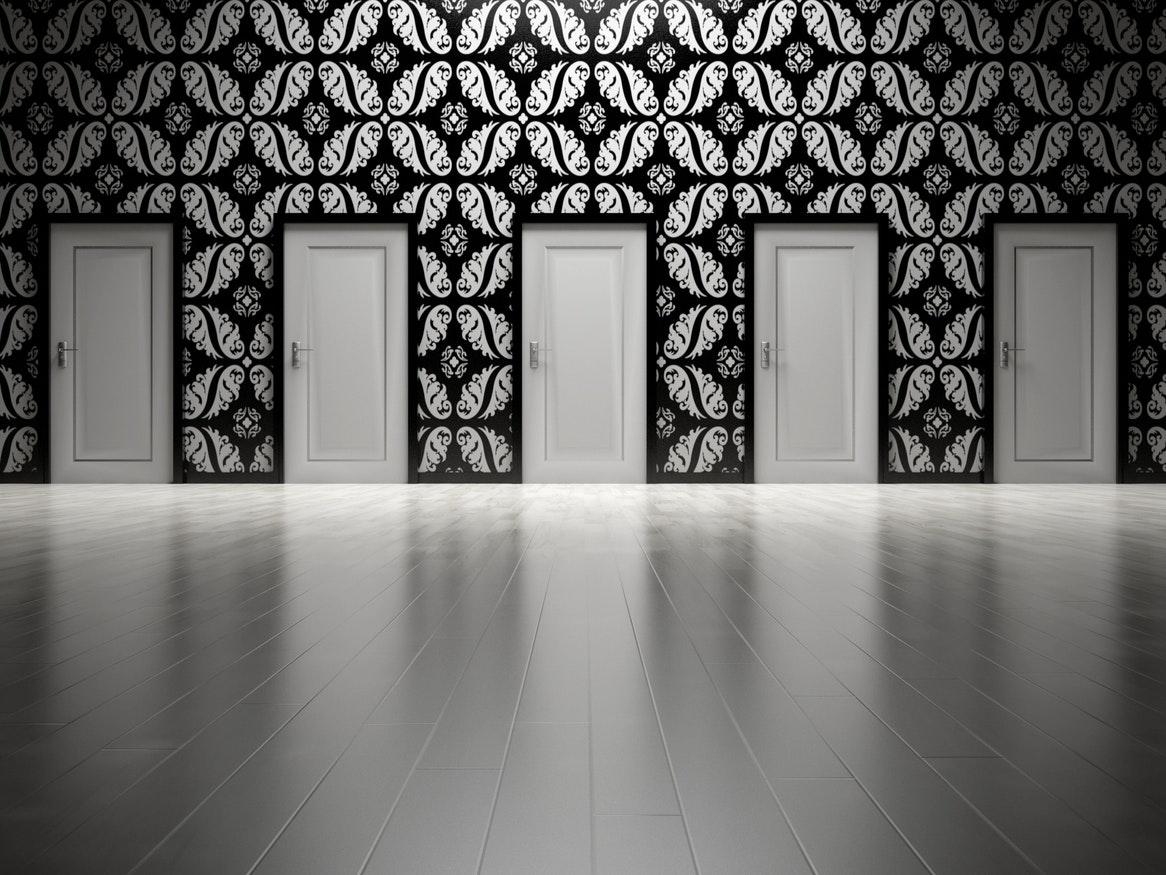 a patterned black and white wall showing five doors