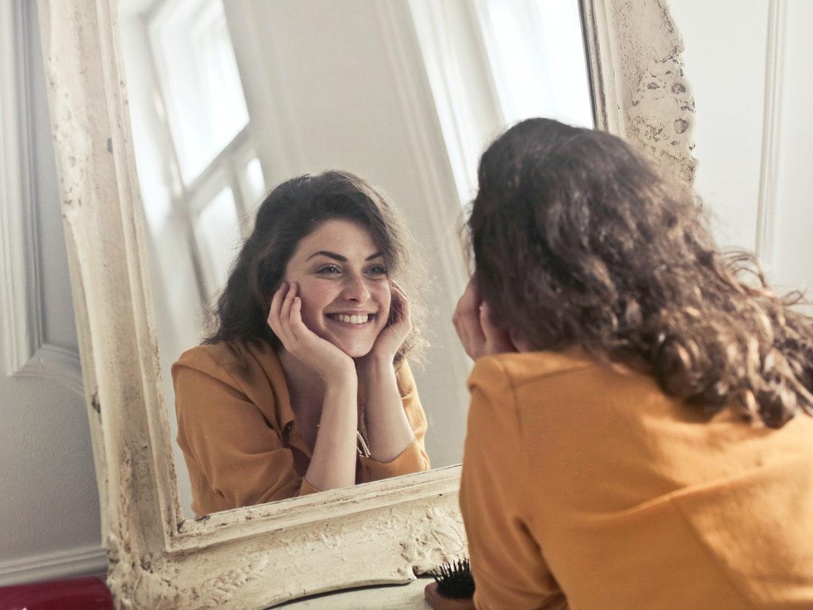 Young woman smiling at herself in a mirror's reflection