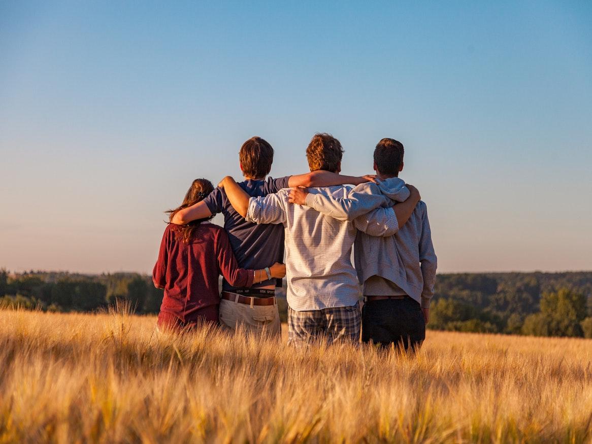 A group huddled together in a field watching the sunset.