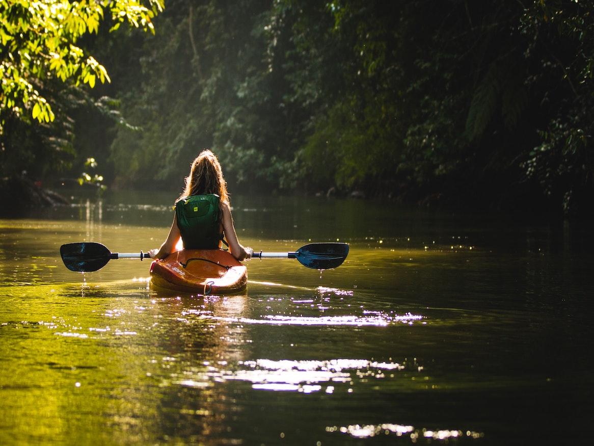 A woman kayaking along a river.