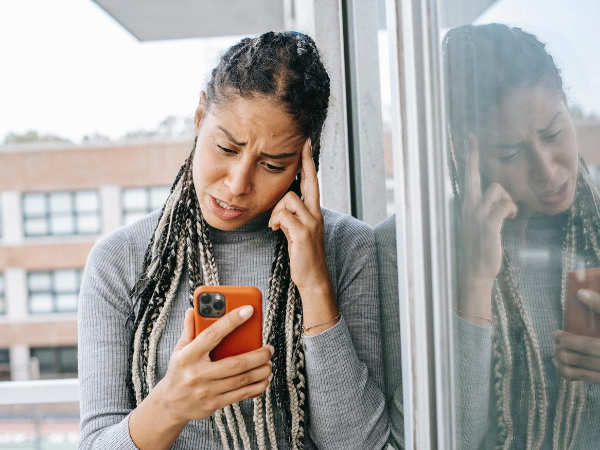 Woman looking at her phone confusedly