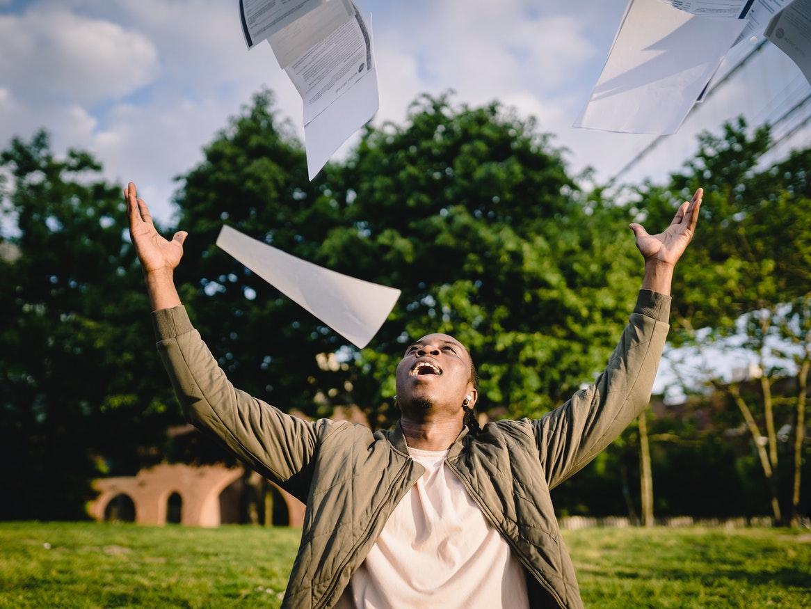 Young adult man throwing papers into the air 