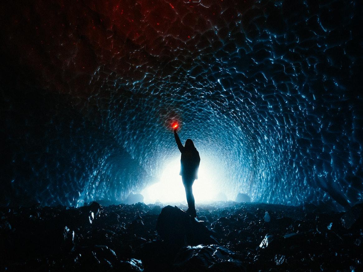 A person holding a lantern in a cave.