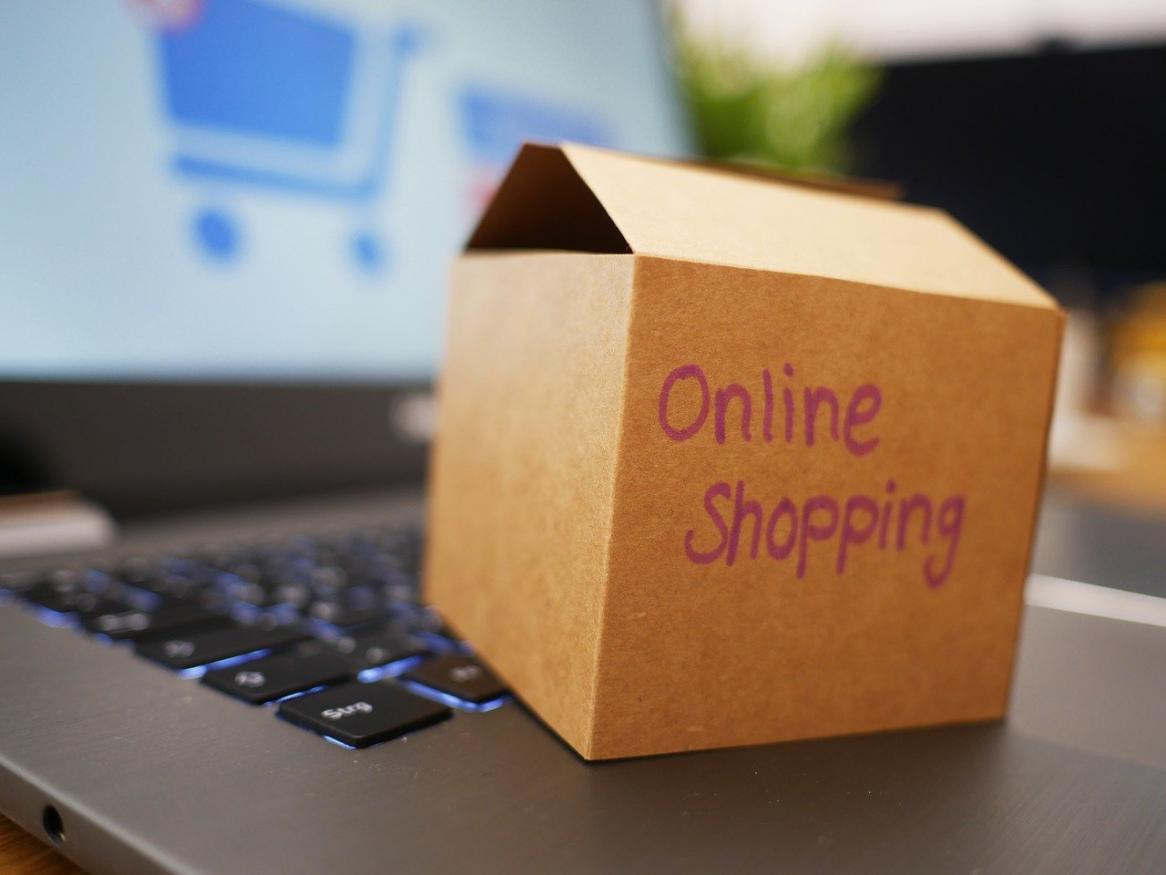 A cardboard box labelled 'Online Shopping' sits on a laptop.