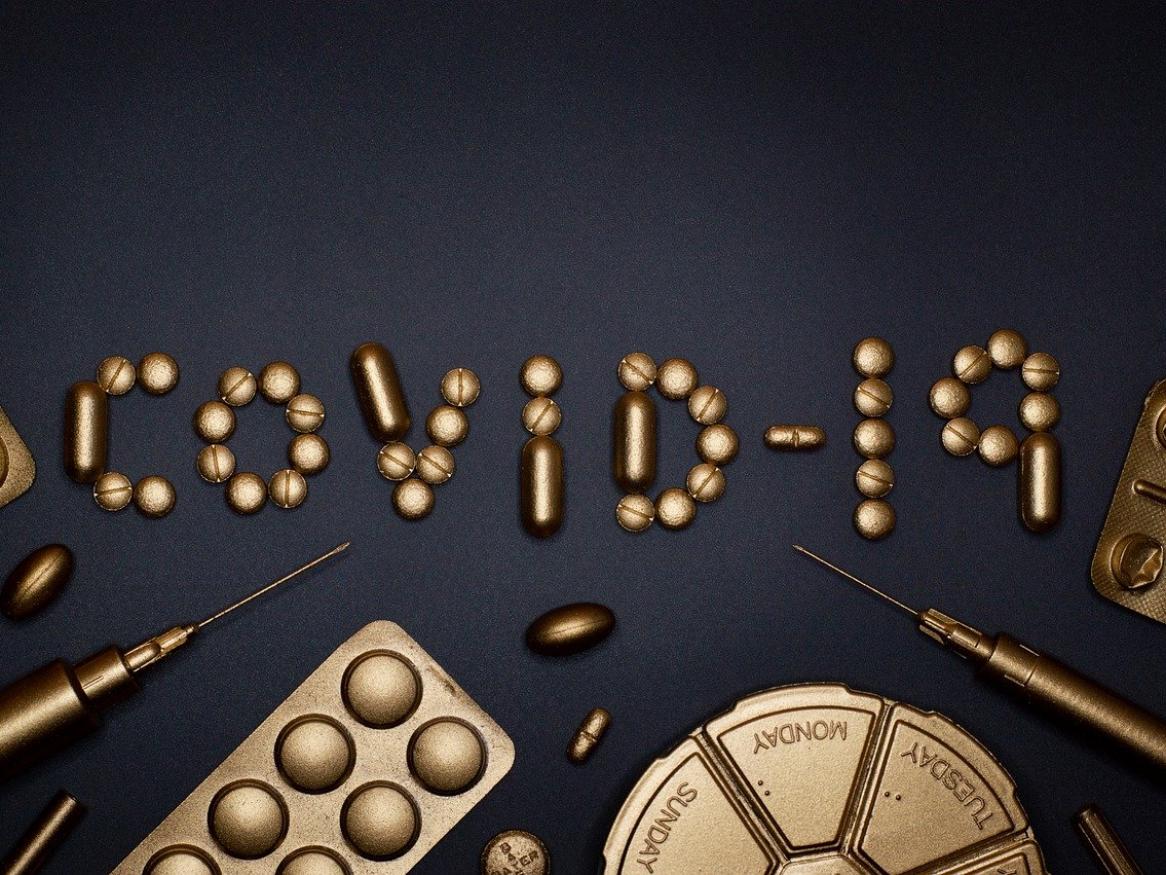 A group of pills on a table in the formation of the word 'COVID-19'.