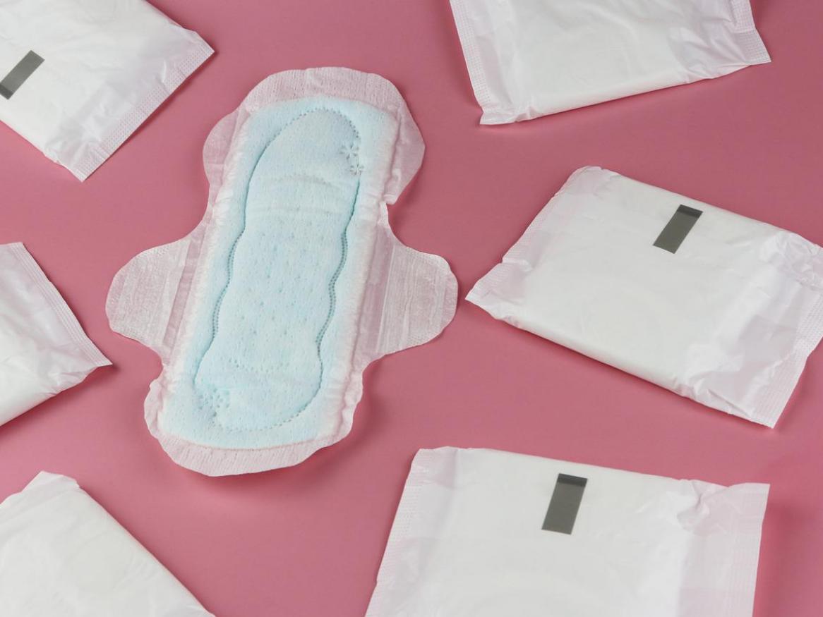 An open sanitary pad and closed pads on a pink background.