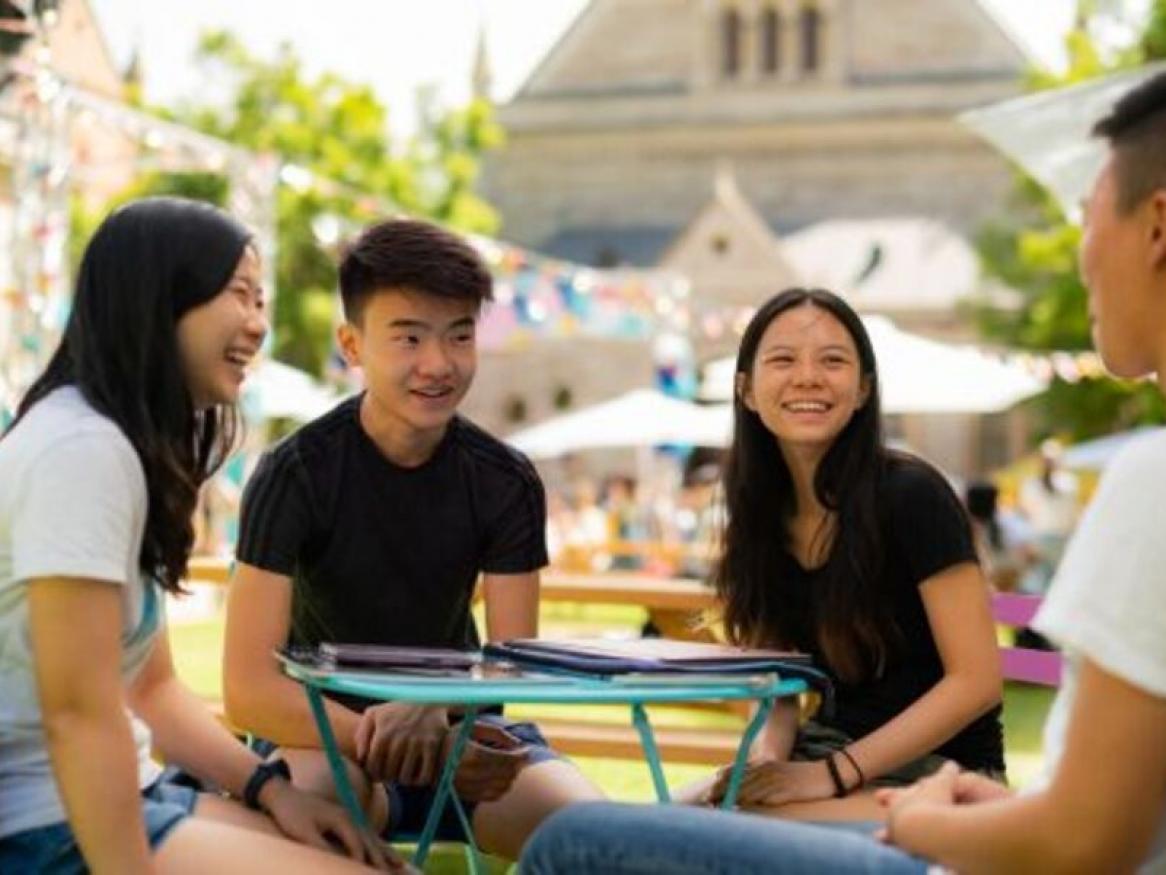 Photo of 4 people sitting around a table on uni campus laughing with each other