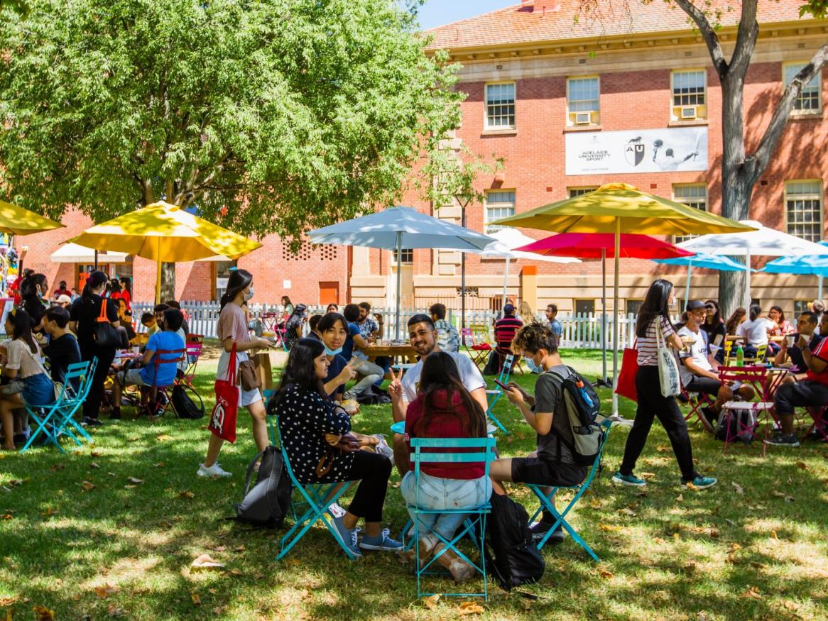 YouX event, Barr Smith lawns, photo with tables, chairs and people talking under umbrellas